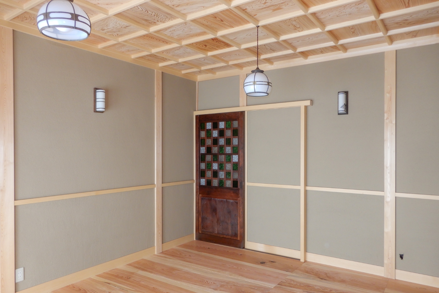 上部がアールになっていた出入口にベニヤの突板のフラッシュ戸だったものを、引き戸に改修。「引き戸は空間が十分に使えて狭い日本家屋には最適」。市松模様の硝子が使われている時代物の蔵戸を入れました。